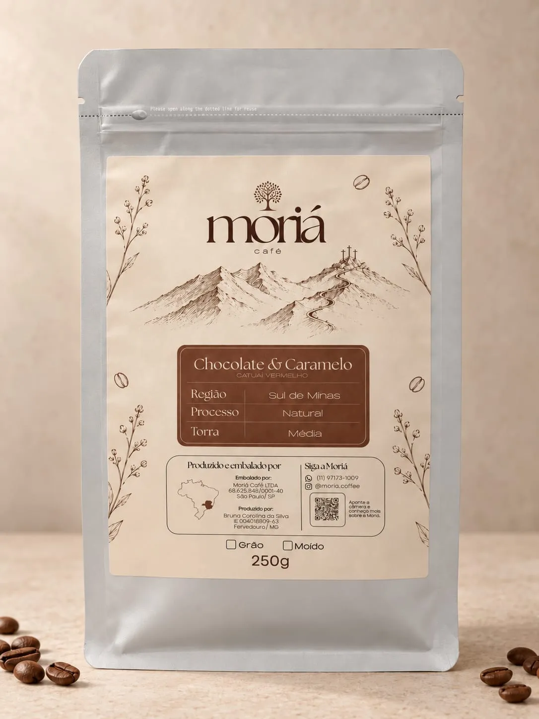 Embalagem do Moriá Gourmet, pacote de 250g, com grãos de café torrados sobre a mesa.